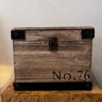 Modern wood storage box with dark steel corner accents and black lettering, styled as functional industrial decorative storage