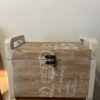 Country style wooden storage chest with a natural wood finish and decorative white word patterns on the sides, used as versatile rustic furniture