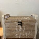 Country style wooden storage chest with a natural wood finish and decorative white word patterns on the sides, used as versatile rustic furniture