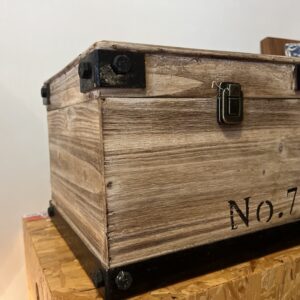 Modern wood storage box with dark steel corner accents and black lettering, styled as functional industrial decorative storage