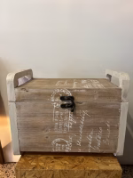 Country style wooden storage chest with a natural wood finish and decorative white word patterns on the sides, used as versatile rustic furniture