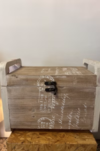 Country style wooden storage chest with a natural wood finish and decorative white word patterns on the sides, used as versatile rustic furniture