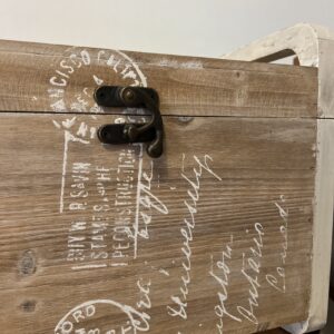 Country style wooden storage chest with a natural wood finish and decorative white word patterns on the sides, used as versatile rustic furniture