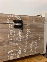Country style wooden storage chest with a natural wood finish and decorative white word patterns on the sides, used as versatile rustic furniture