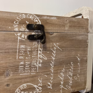 Country style wooden storage chest with a natural wood finish and decorative white word patterns on the sides, used as versatile rustic furniture