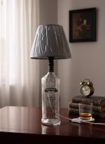 Handmade side lamp crafted from a Smirnoff repurposed spirit bottle with a fabric lampshade, displayed as unique sustainable lighting decor