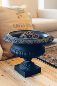 Large 47cm matte black cast iron garden urn with a scrolled rim and fluted body, styled as an entryway centerpiece on a stone pedestal