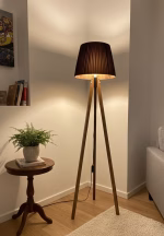Handmade tripod floor lamp with solid walnut wood legs and a dark pleated fabric lampshade, styled in a modern living room corner