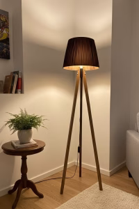 Handmade tripod floor lamp with solid walnut wood legs and a dark pleated fabric lampshade, styled in a modern living room corner