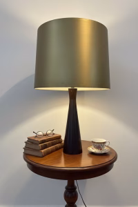 Large vintage Mid-Century Modern table lamp with a tapered conical steel base and a wide, reflective gold-finished steel lampshade on a console table