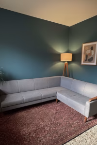 Newly refurbished Mid-Century Modern L-shaped sectional sofa with gray upholstery and solid mahogany wood frame, styled in a corner living room setting