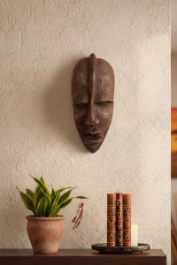 Large hand-carved African tribal mask in solid dark wood with an elongated design and matte finish, mounted as cultural wall art