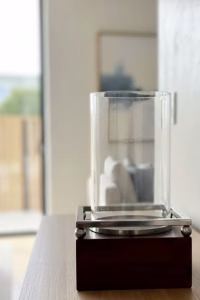 Modern rustic hurricane candle holder with a dark wood base, spherical metal feet, and a large glass cylinder sleeve, 42.5cm tall