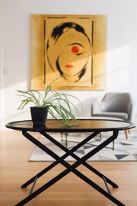 Luxury oval black leather folding table with visible perimeter stitching and black metal X-frame, styled in a modern masculine library or lounge