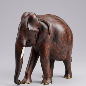 Hand-carved solid wood elephant sculpture with detailed natural grain, delicate inlay work on the feet, and polished tusks from RockFort Lebanon.