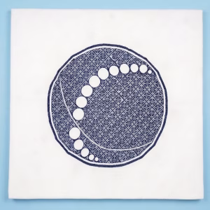 Large hand-embroidered textile wall hanging featuring a navy blue circular mandala and moon-phase design on a white fabric base from RockFort boutique in Lebanon.
