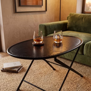 Sophisticated oval foldable coffee table with a hand-stitched black leather top and minimalist metal frame from RockFort vintage furniture store in Lebanon.