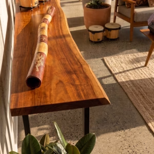 Premium master-crafted Aboriginal didgeridoo featuring bold ochre-toned bands and traditional lizard motifs set against deep earth-red panels from RockFort Lebanon