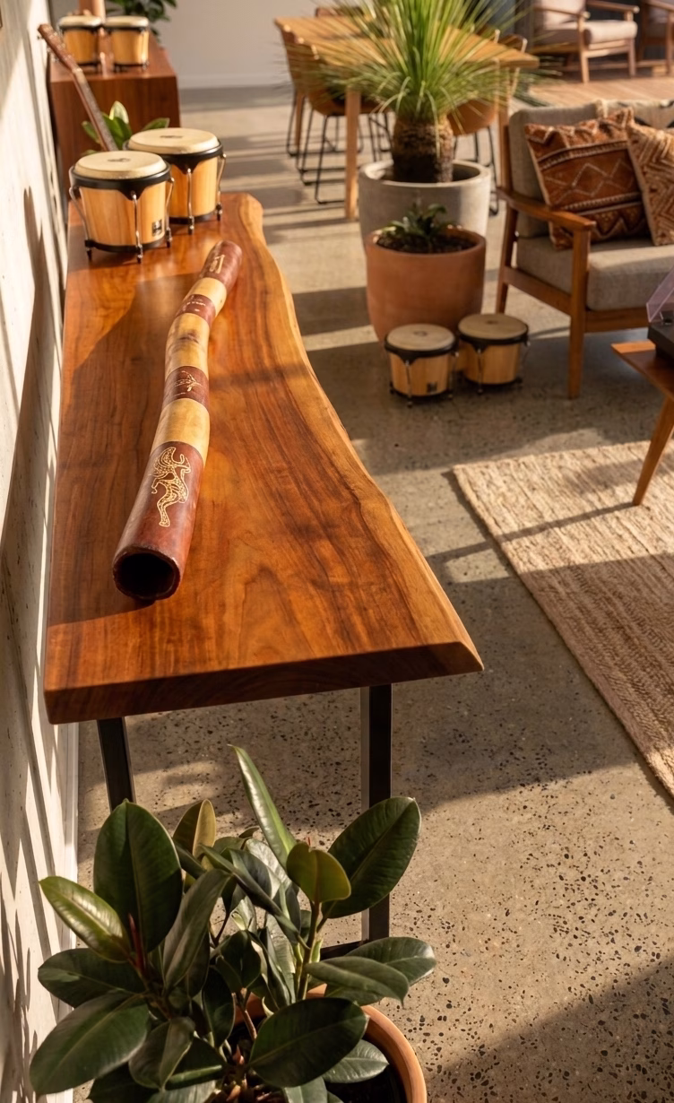 Premium master-crafted Aboriginal didgeridoo featuring bold ochre-toned bands and traditional lizard motifs set against deep earth-red panels from RockFort Lebanon