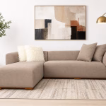Modern beige L-shaped corner sofa with a minimalist design, deep seating cushions, and a subtle wooden base from RockFort furniture store in Lebanon.