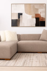 Modern beige L-shaped corner sofa with a minimalist design, deep seating cushions, and a subtle wooden base from RockFort furniture store in Lebanon.