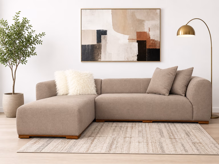 Modern beige L-shaped corner sofa with a minimalist design, deep seating cushions, and a subtle wooden base from RockFort furniture store in Lebanon.