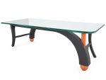 Side view of the glass coffee table showing sweeping arched charcoal grey legs and salmon orange ball feet from RockFort Lebanon.