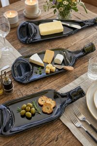 Three dark melted wine bottle trays served with cheese, butter, olives and crackers on a rustic dining table from RockFort Lebanon.