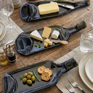 Three dark melted wine bottle trays served with cheese, butter, olives and crackers on a rustic dining table from RockFort Lebanon.