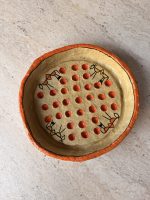 Top view of the Warli papier-mâché bowl with stick-figure folk art and a grid of raised red dots on a stone surface from RockFort Lebanon.
